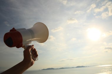 Deniz su altında gökyüzü arka plan üzerinde megafon tutan el