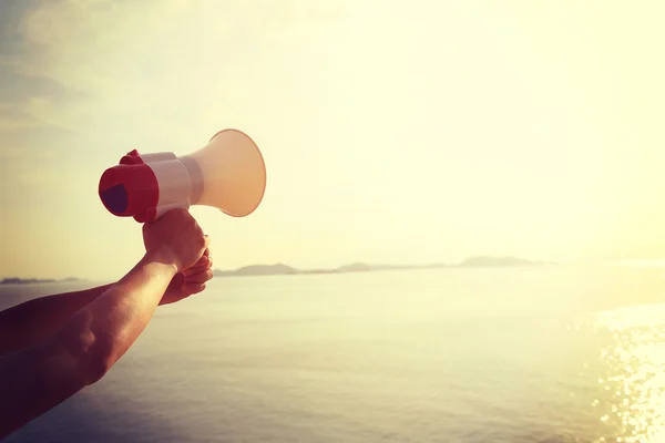 Mãos segurando megafone sobre o mar — Fotografia de Stock