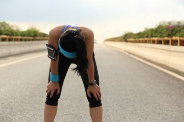 Şehir yolda zor çalıştırdıktan sonra dinlenme alarak yorgun kadın runner