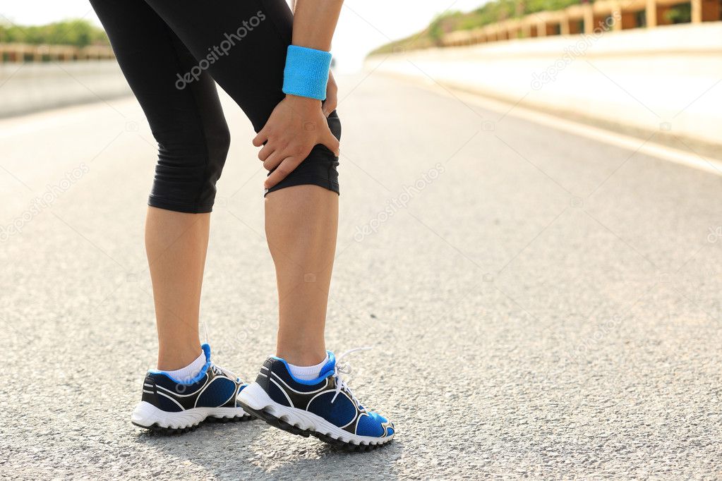Woman runner holding injured leg