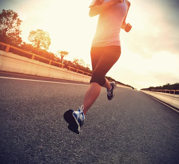 Atleta feminino correndo na estrada à beira-mar — Fotografia de Stock