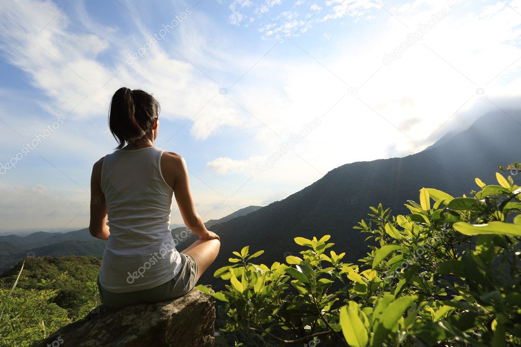 young woman practicing yoga at sunrise mountain peak