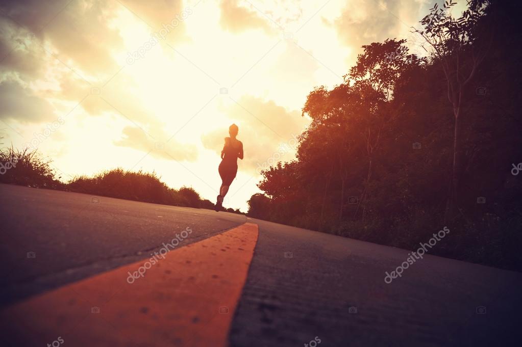 Female athlete running at seaside road.