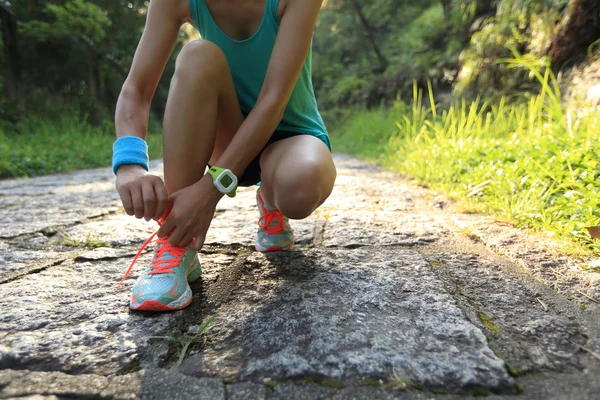 Giovane donna corridore allacciatura lacci delle scarpe — Foto Stock