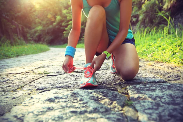 Young woman runner tying shoelaces — Stock Photo, Image