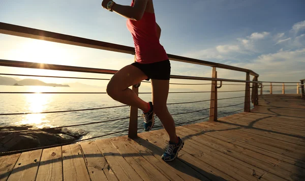 年轻的健身女性腿部运行日出海边的小路上 — 图库照片