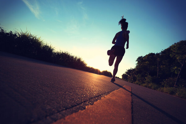 Young fitness woman running on sunrise