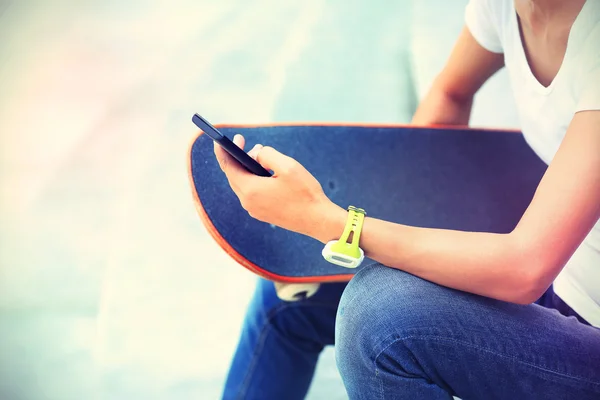 Mujer skateboarder utilizando el teléfono inteligente —  Fotos de Stock