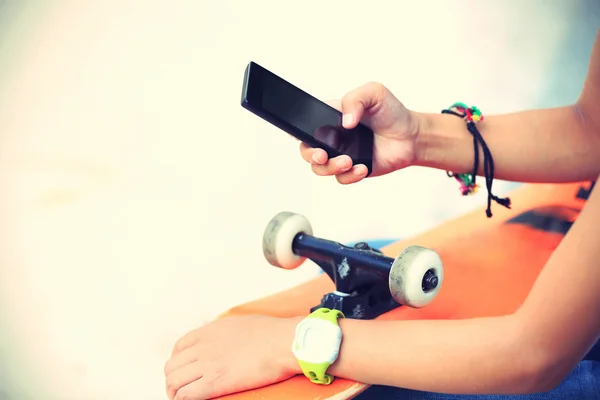 Kvinnan skateboardåkare med smart telefon — Stockfoto