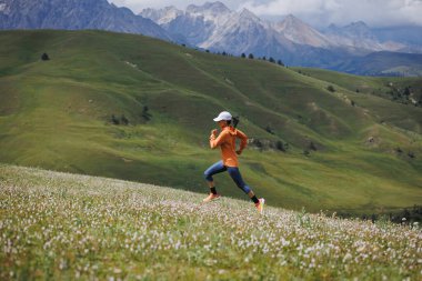Yüksek rakımlı çayırlarda koşan kadın koşucu.