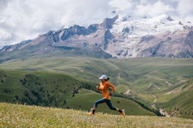 Yüksek rakımlı çayırlarda koşan kadın koşucu.