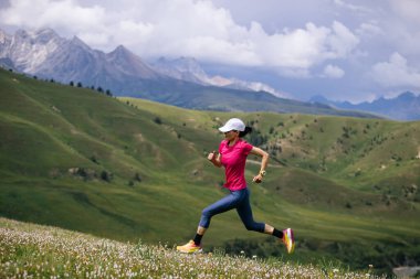 Yüksek rakımlı çayırlarda koşan kadın koşucu.