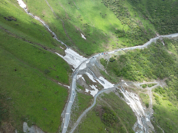 Вид с воздуха на извилистую дорогу на красивой высокогорной травянистой горе