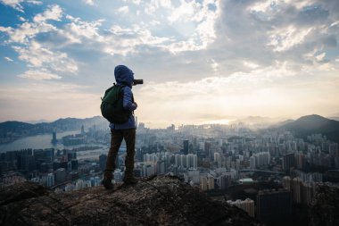 Hong Kong 'da dağ yamacına tırmanan sırt çantalı adam, şehir mimarisinde nefes kesici bir manzara. 