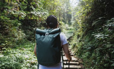 Sırt çantalı bir kadın tırmanma taşıyla dik bir orman yoluna çıkıyor..