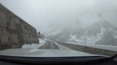 Kar ve buzla kaplı sarmal dağ yolu yoğun kış sisinde kayboluyor..
