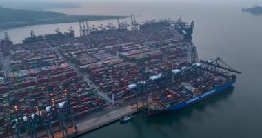 Sayısız konteynır, kanat vinci ve büyük bir kargo gemisinin bulunduğu büyük bir nakliye limanının havadan görüntüsü..