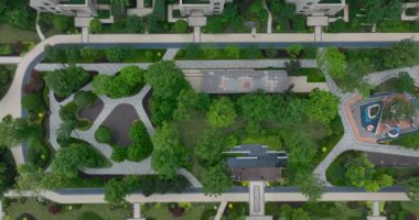 Yeşil bir bahçeyi çevreleyen uzun, beyaz apartman binalarını gösteren bir yerleşim merkezinin yukarıdan görünüşü..