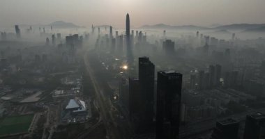 Yoğun bir şehir silueti ve merkez yol üzerinde puslu, sıcak gün batımı ya da gün doğumu manzarası. Çin