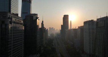 Yoğun bir şehir silueti ve merkez yol üzerinde puslu, sıcak gün batımı ya da gün doğumu manzarası. Çin