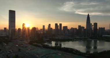 Gün doğumunda sisli, güneşli gökdelenler arasında uzanan geniş bir yol var..