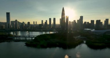 Gün doğumunda sisli, güneşli gökdelenler arasında uzanan geniş bir yol var..