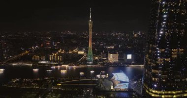 Canlı bir şehir merkezi ve geceleri aydınlatılan gökdelenlerin geniş hava manzarası. .