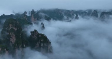 Pürüzlü dağ zirveleri yoğun, ürkütücü bir alçak asılı bulut tabakasından ya da sisten ortaya çıkar. .