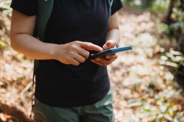 Sonbahar ormanlarında akıllı telefon kullanan bir yürüyüşçü.