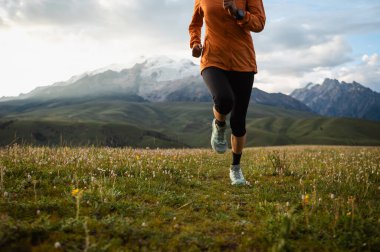 Yüksek rakımlı çayırlarda koşan kadın koşucu.