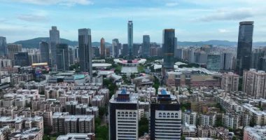 İki modern cam gökdelen bulutlu gökyüzü altında yoğun bir şehir siluetine hükmediyor.