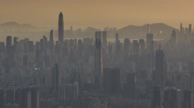 Çok sayıda gökdelenin ve puslu bir gökyüzünün altında yüksek, farklı bir kulenin yer aldığı yoğun şehir manzarası.