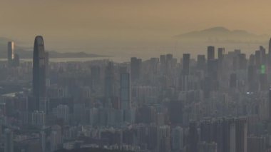 Çok sayıda gökdelenin ve puslu bir gökyüzünün altında yüksek, farklı bir kulenin yer aldığı yoğun şehir manzarası.