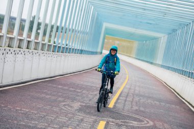 Bisiklet yolunda bisiklet süren neşeli bir kadın.