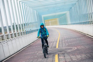 Bisiklet yolunda bisiklet süren neşeli bir kadın.