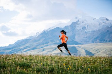 Yüksek rakımlı çayırlarda koşan kadın koşucu.