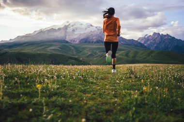 Yüksek rakımlı çayırlarda koşan kadın koşucu.