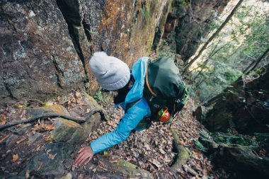 Sırt çantalı bir kadın dik orman patikasında yürüyüş yapıyor.