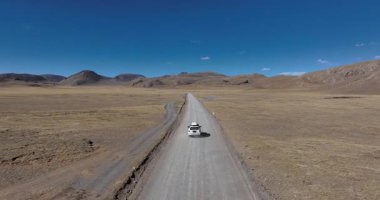 Yüksek irtifada göl kenarında çalışan off-road aracının hava görüntüleri.