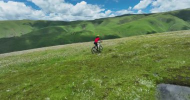 Güzel çayırlarda ve orman dağlarında bisiklet süren bir kadın.