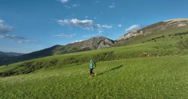 Güzel çayırlarda ve dağlarda sırt çantasıyla gezen kadının hava görüntüleri.