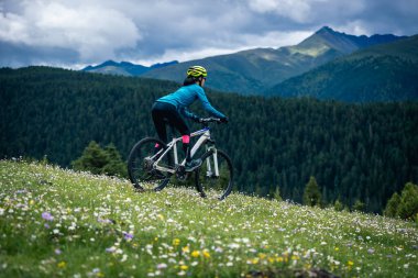 Dağ tepesinde bisiklet süren bir kadın. Ormanın tepesinde.