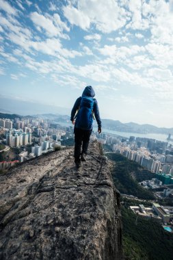 Başarılı kadın yürüyüşçü uçurumun kenarında duruyor kollarını uzatarak güzel Hong Kong 'a doğru.