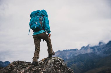 Sırt çantalı bir kadın yüksek rakımlı dağlarda dik yamaçlara tırmanıyor.