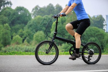 Uzaklarda modern şehirli katlı bisiklet süren bir kadın.