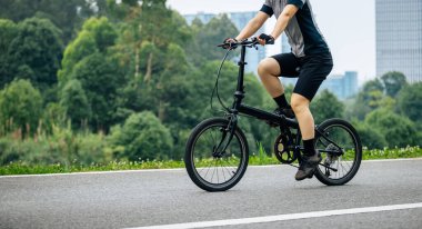 Uzaklarda modern şehirli katlı bisiklet süren bir kadın.