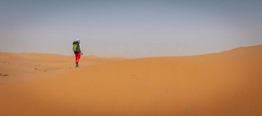 Sırt çantalı bir kadın çölde yürüyüş yapıyor.
