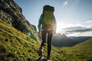 Başarılı bir kadın sırt çantalı. Gün batımı dağlarının tepesinde yürüyüş yapıyor.