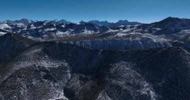 Berrak mavi gökyüzünün altındaki karlı dağ manzarası