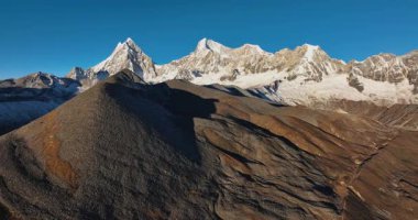 Açık mavi gökyüzünün altında karlı dağlar